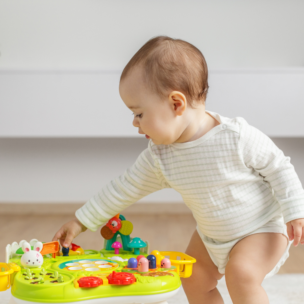 Baby playing with a colorful toy on a light-colored floor.

